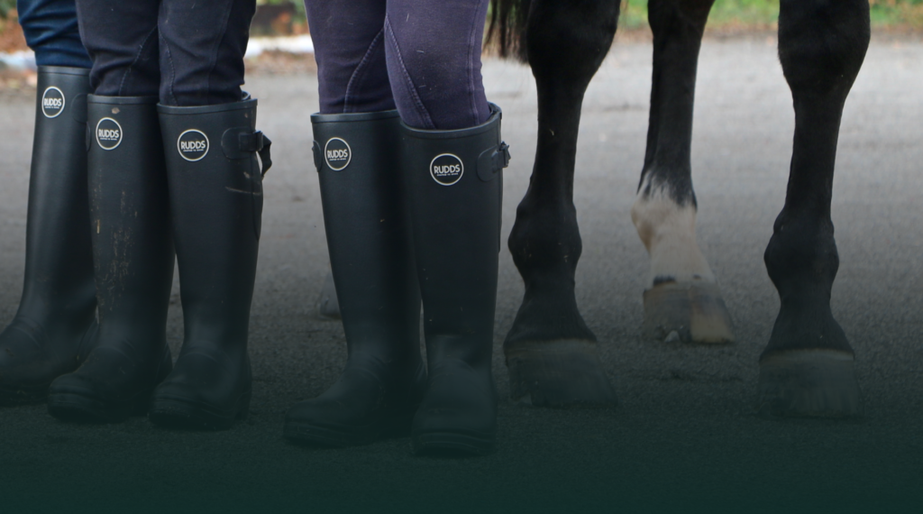 Rudds wellies with logo design worn by two people alongside a horse