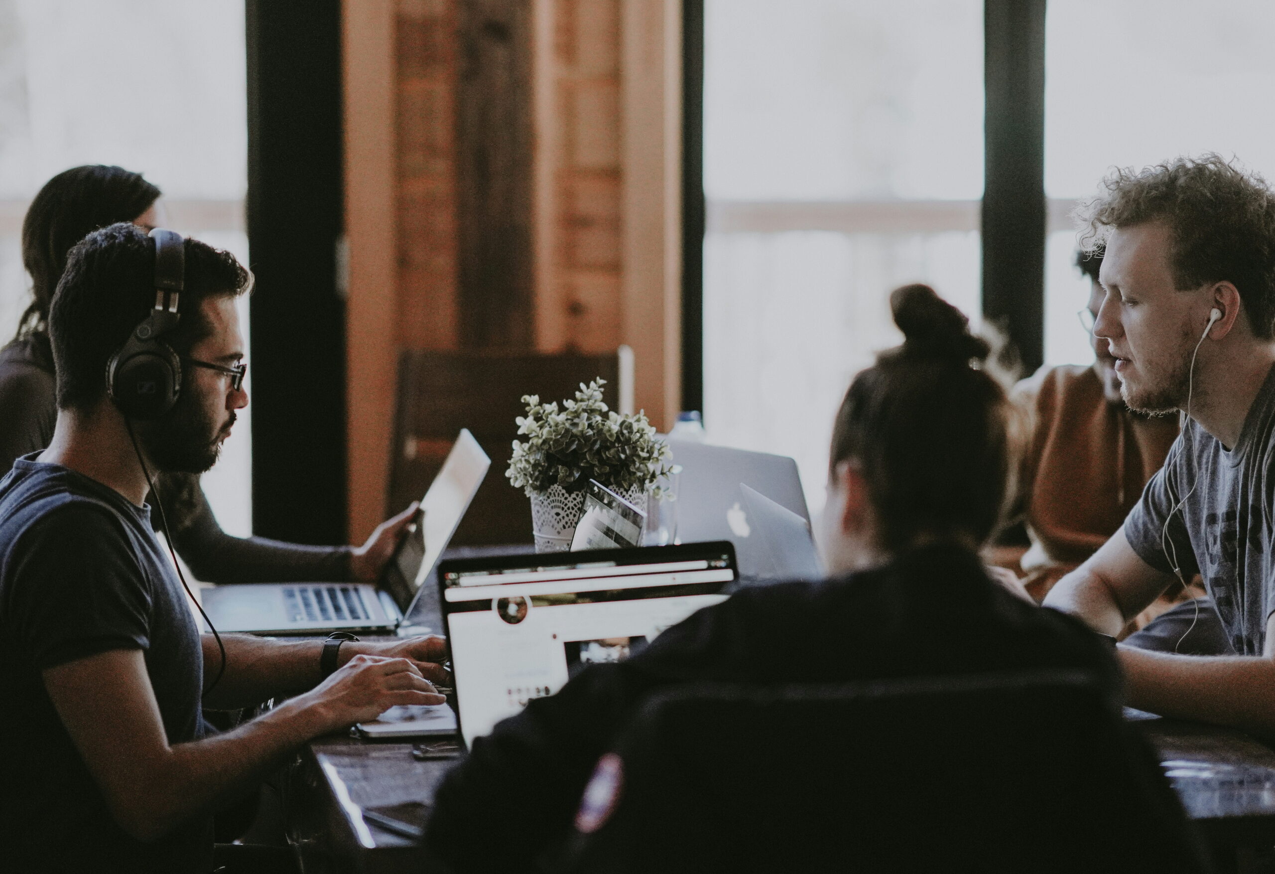 sales and marketing team together, image shows five people around a table with a laptop open in front of the woman