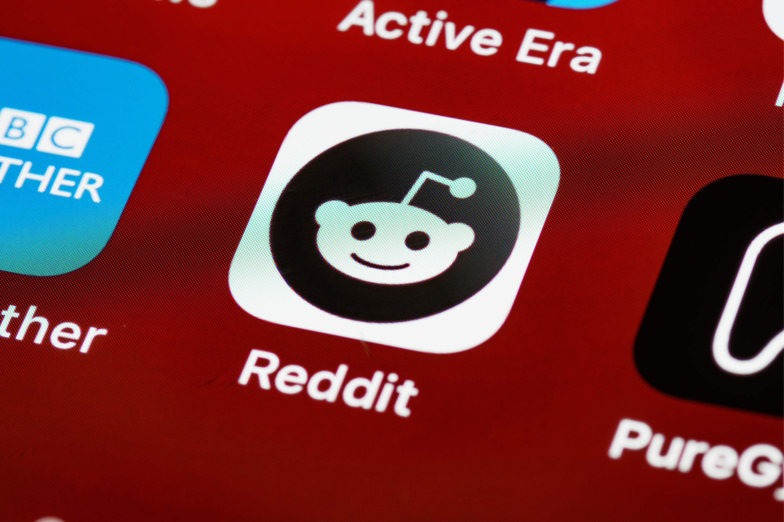 Image of the Reddit app icon amongst other apps on a phone screen